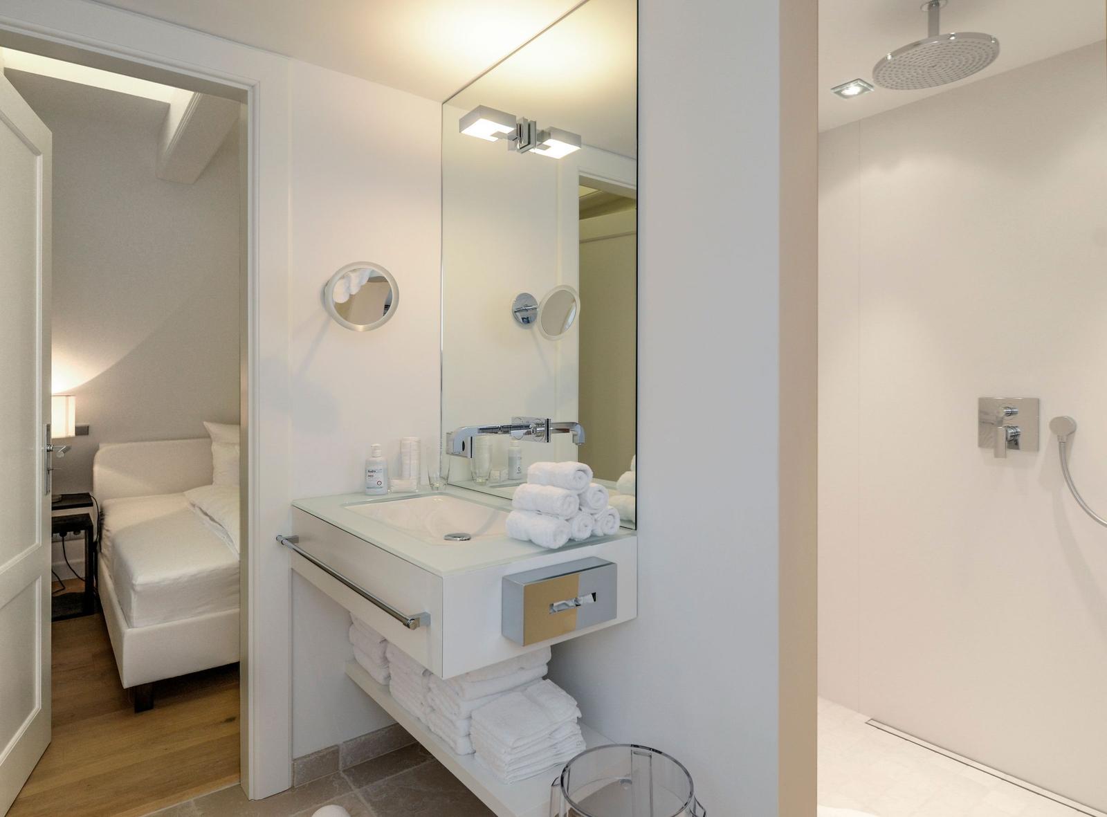 Badezimmer mit Dusche, Waschbecken und Blick in Schlafzimmer
