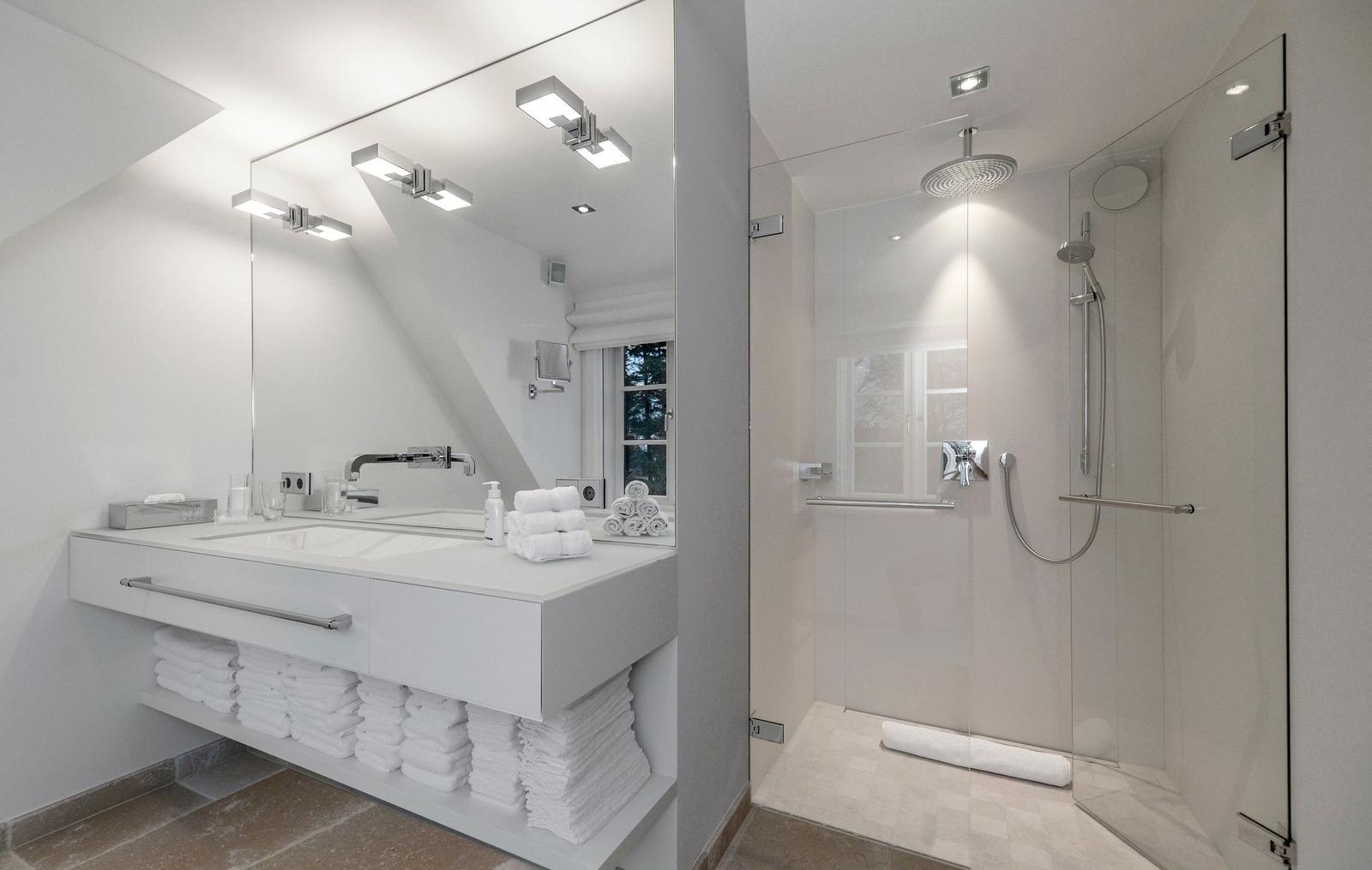 Moderne Dusche mit Glaswand und Waschbecken mit Spiegel.