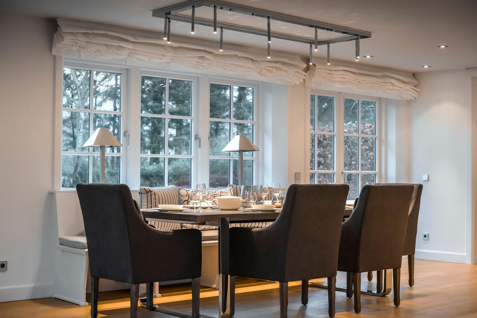 Esszimmer mit Tisch, Stühlen und großen Fenstern