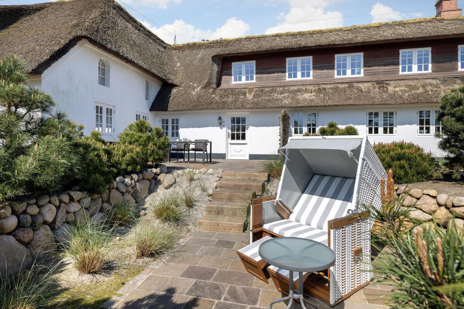 Dorfhaus mit Strohdach, Gartenbereich und Strandkorb.
