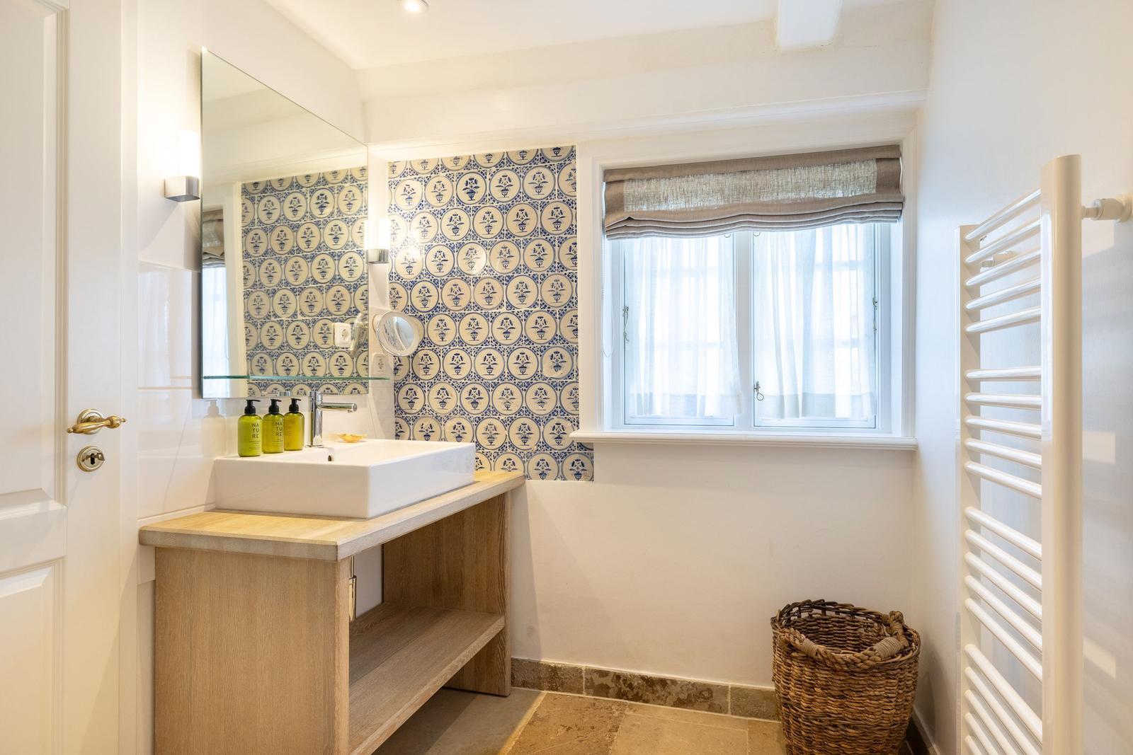 Badezimmer mit Waschtisch, Spiegel und Fenster