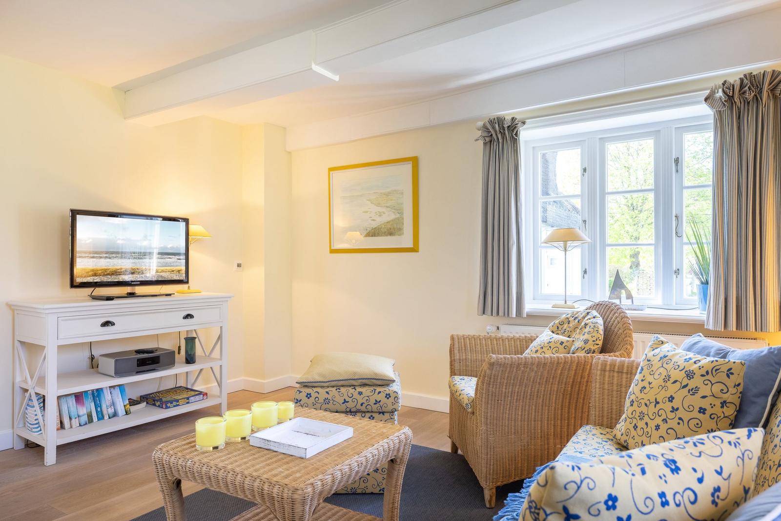 Wohnzimmer mit Wicker-Sofa, Fernseher und Fenster mit Blick.