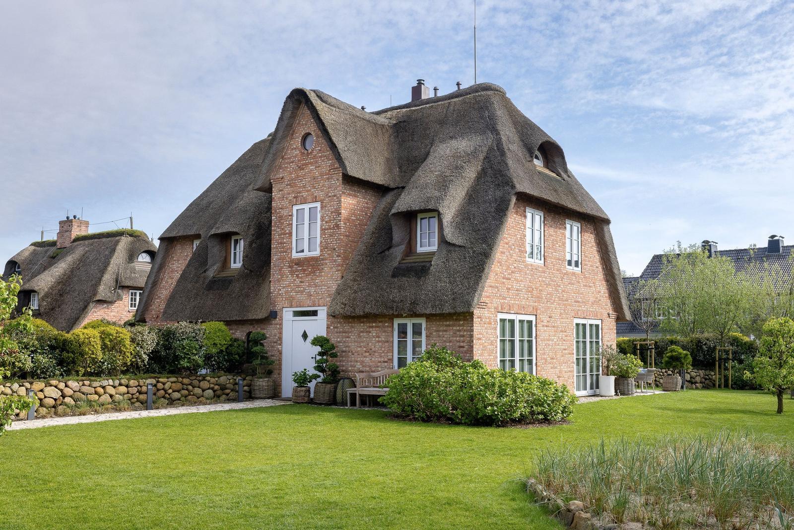 Haus mit Strohdach, weißem Eingang und Garten