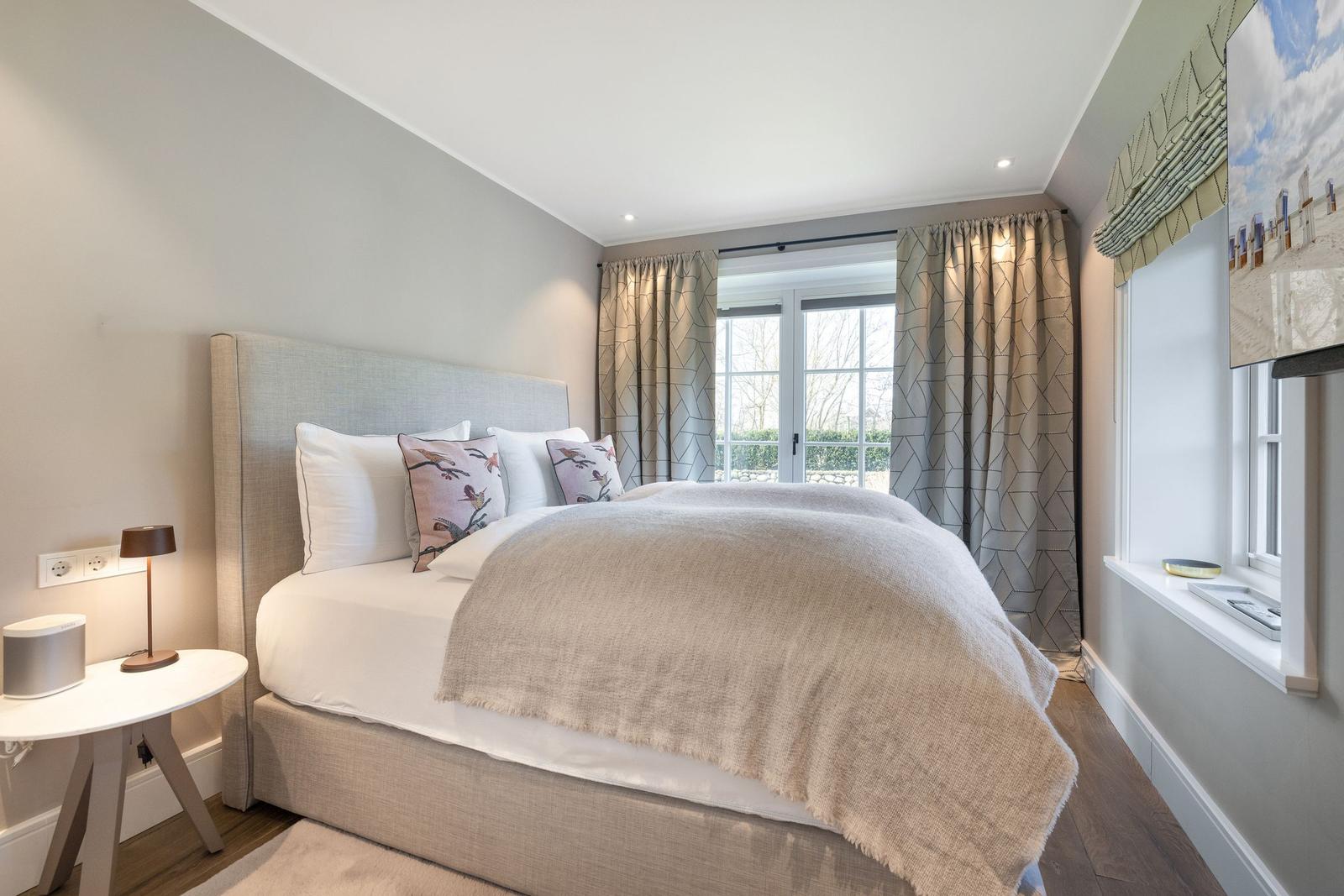 Schlafzimmer mit Bett, Vorhängen und Fenster zur Außenseite.