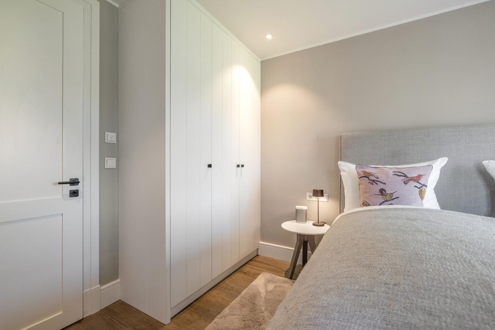 Schlafzimmer mit Bett, Nachttisch und Kleiderschrank.