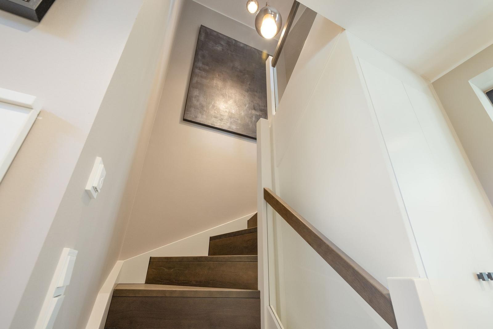 Helle Treppe mit Holzstufen und moderner Wandbeleuchtung.