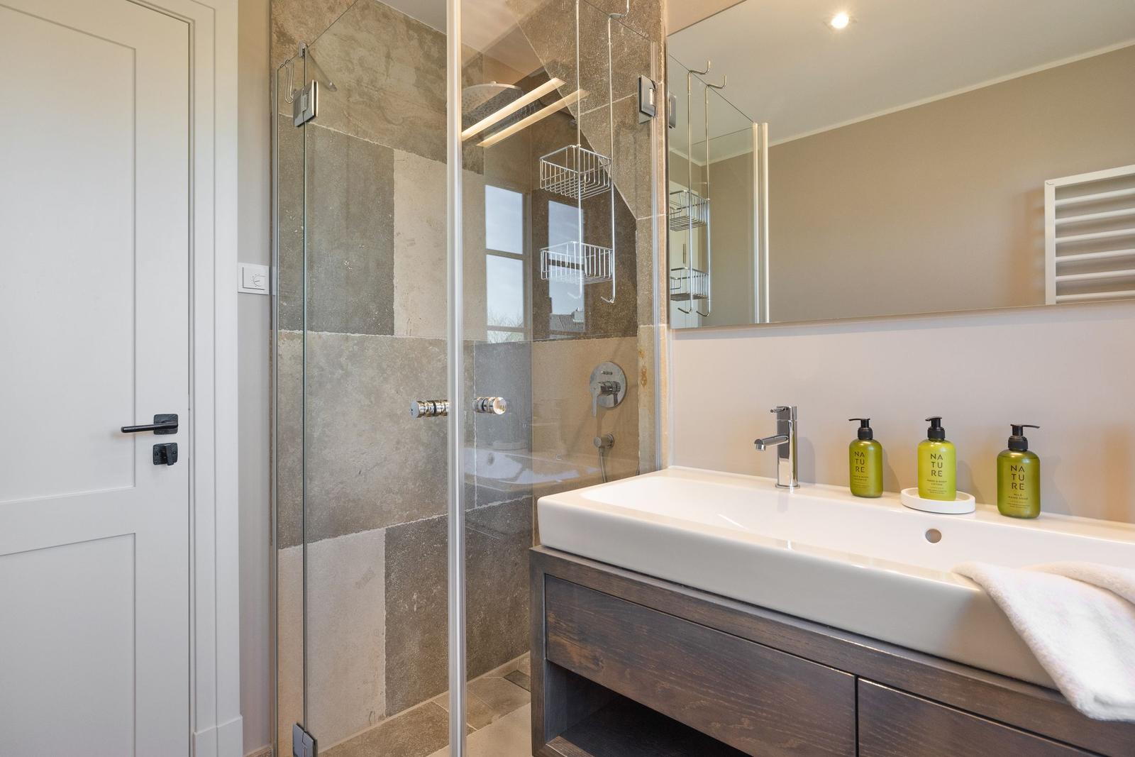 Badezimmer mit Dusche, Waschbecken und Spiegel.