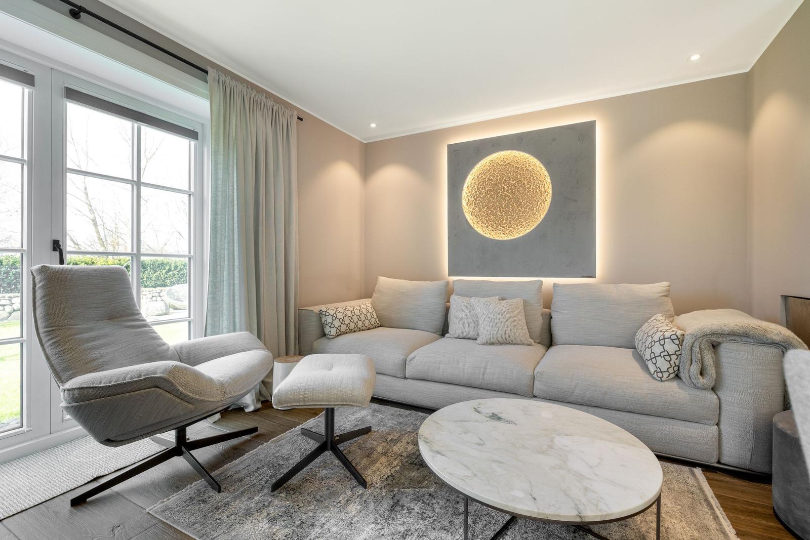 Ein Wohnzimmer mit Sofa, Sessel und runden Tisch.