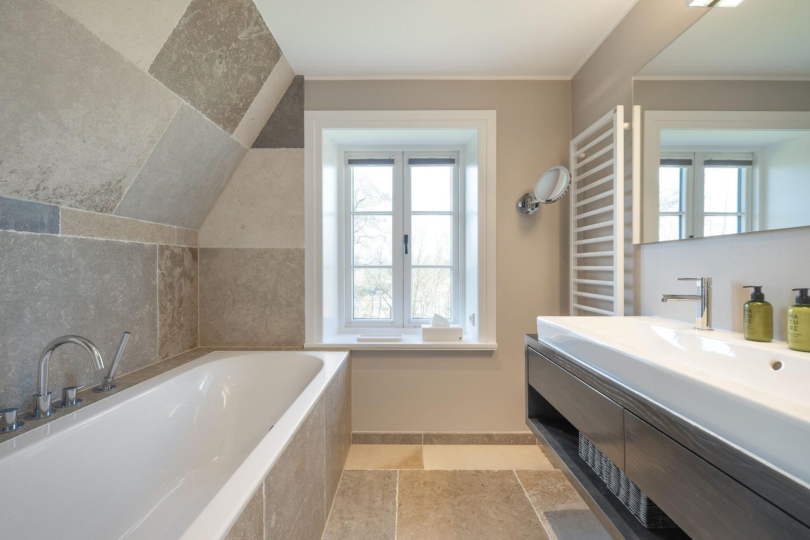 Badezimmer mit Badewanne, Waschbecken und Fenster