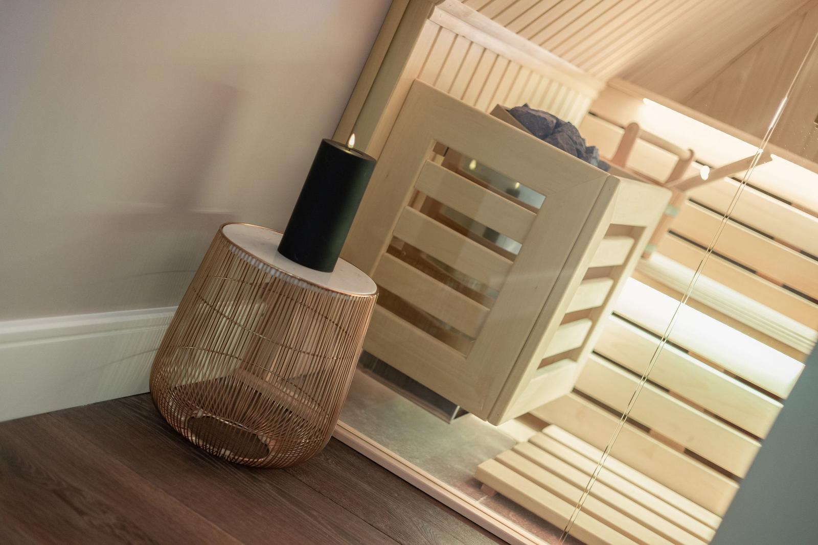 Sauna mit Holzbank und dekorativer Lampe im Vordergrund.