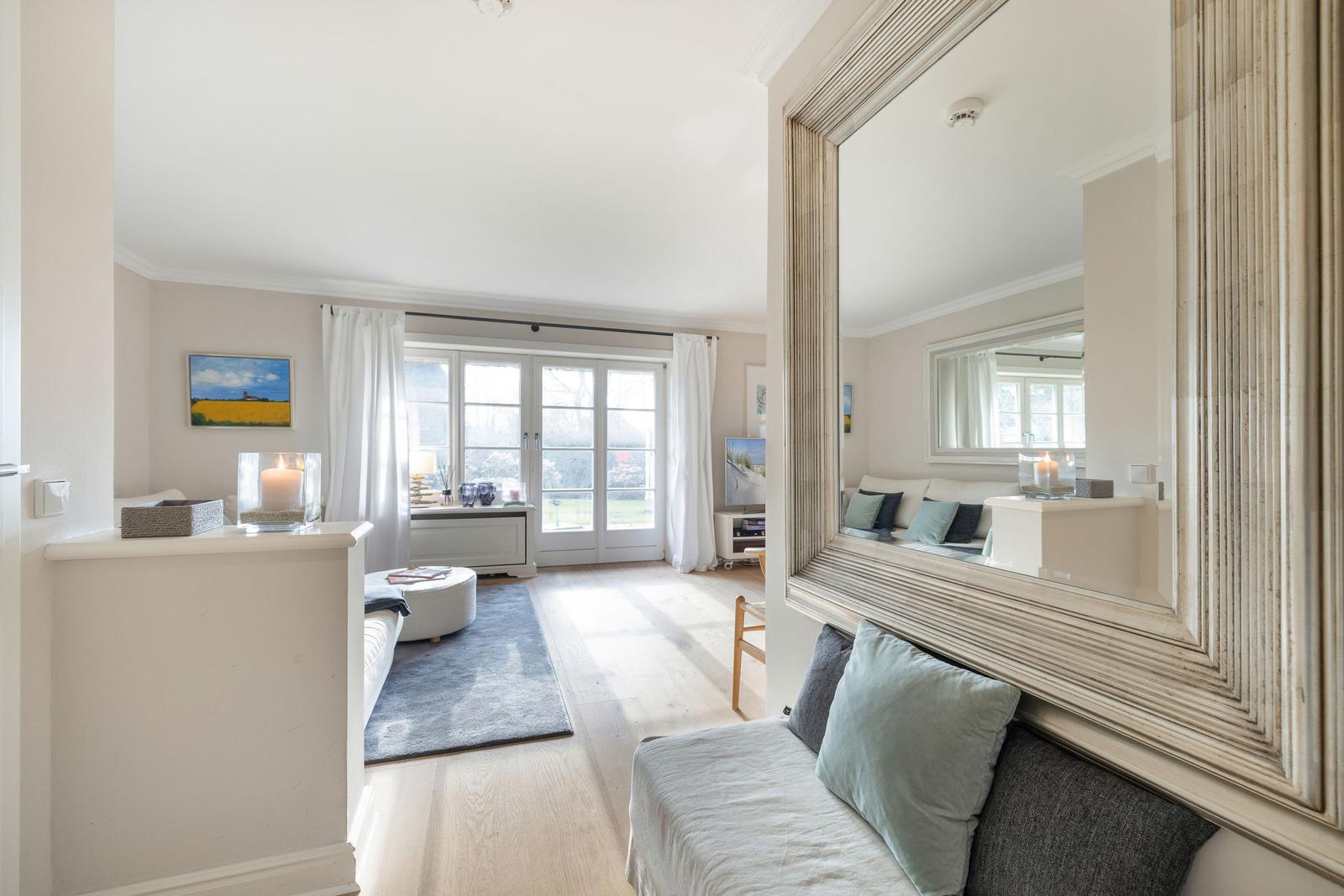 Living room with large windows, mirror, and sofa.