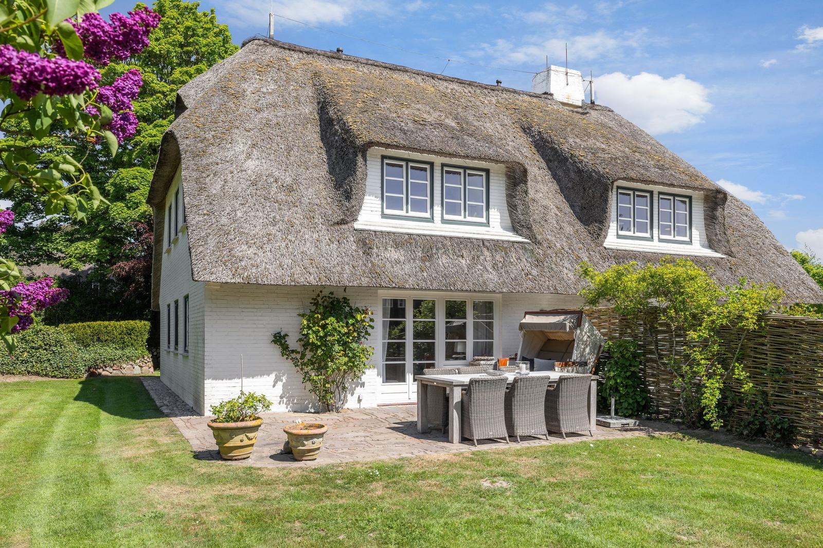 House with thatched roof, terrace, and garden. Grill and seating area.
