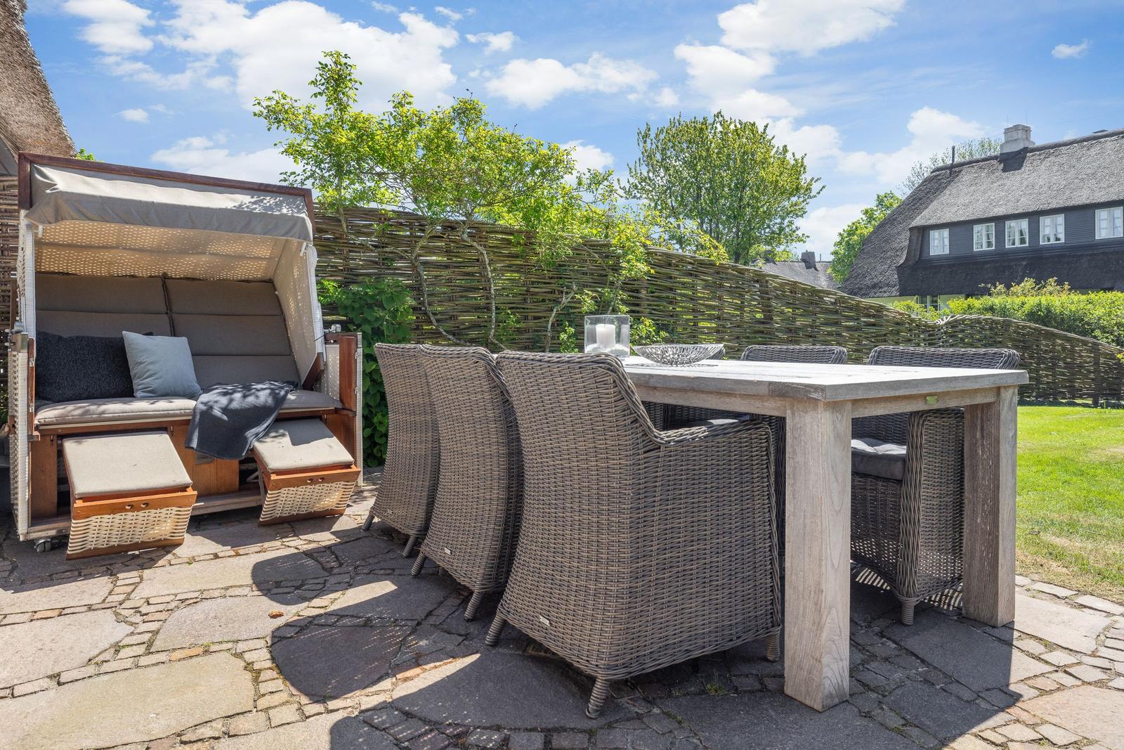 Terrace with garden furniture, sun shelter, and stone paving.