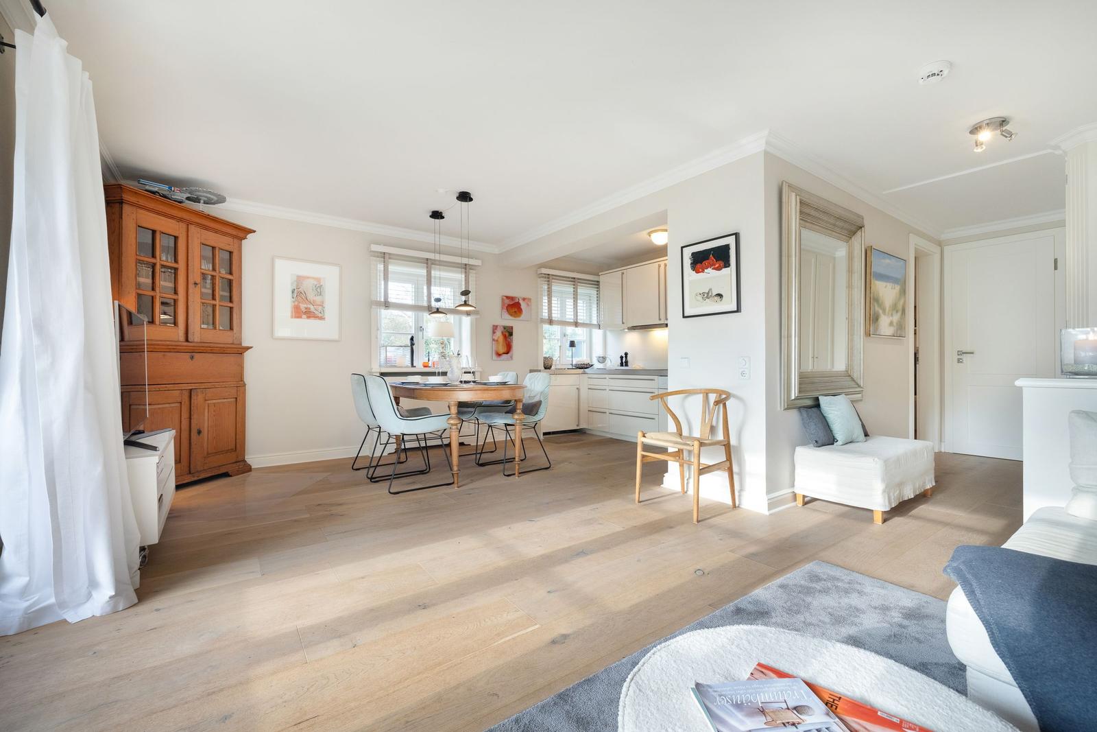 Living and dining area with wooden floor, dining table, and kitchen area.