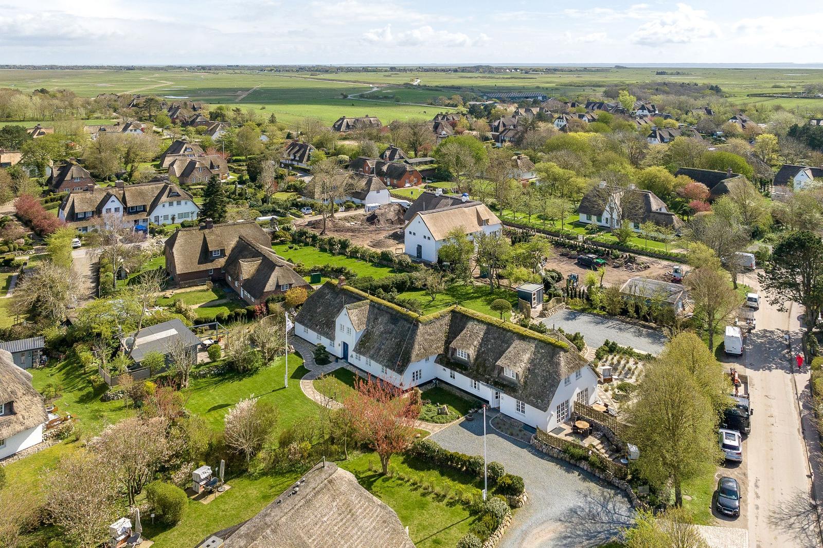 Dorf mit strohgedeckten Häusern und grünen Gärten