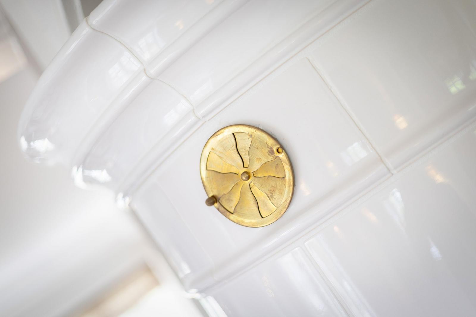 Goldener Ventilator auf weißer Fliesenwand