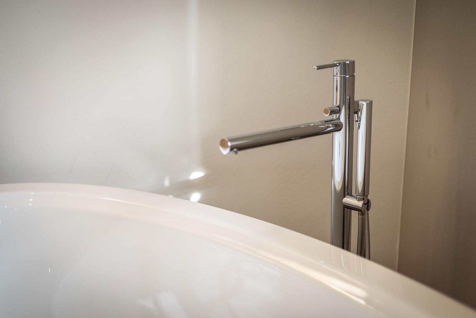 Moderne Dusche mit hochwertigem Wasserhahn und glänzendem Waschbeckenrand.