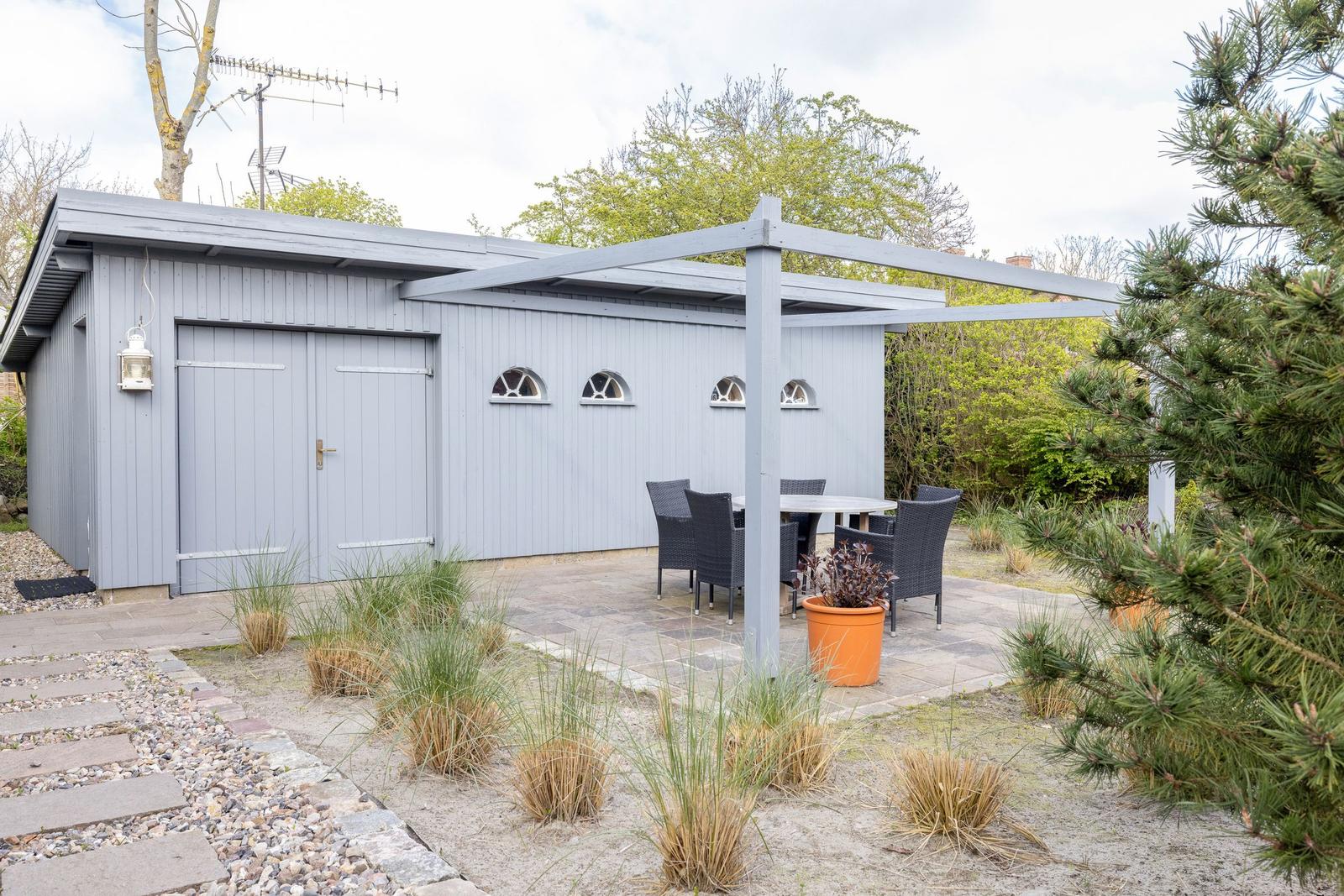 Graue Hütte mit Sitzgelegenheit unter Pavillon im Garten