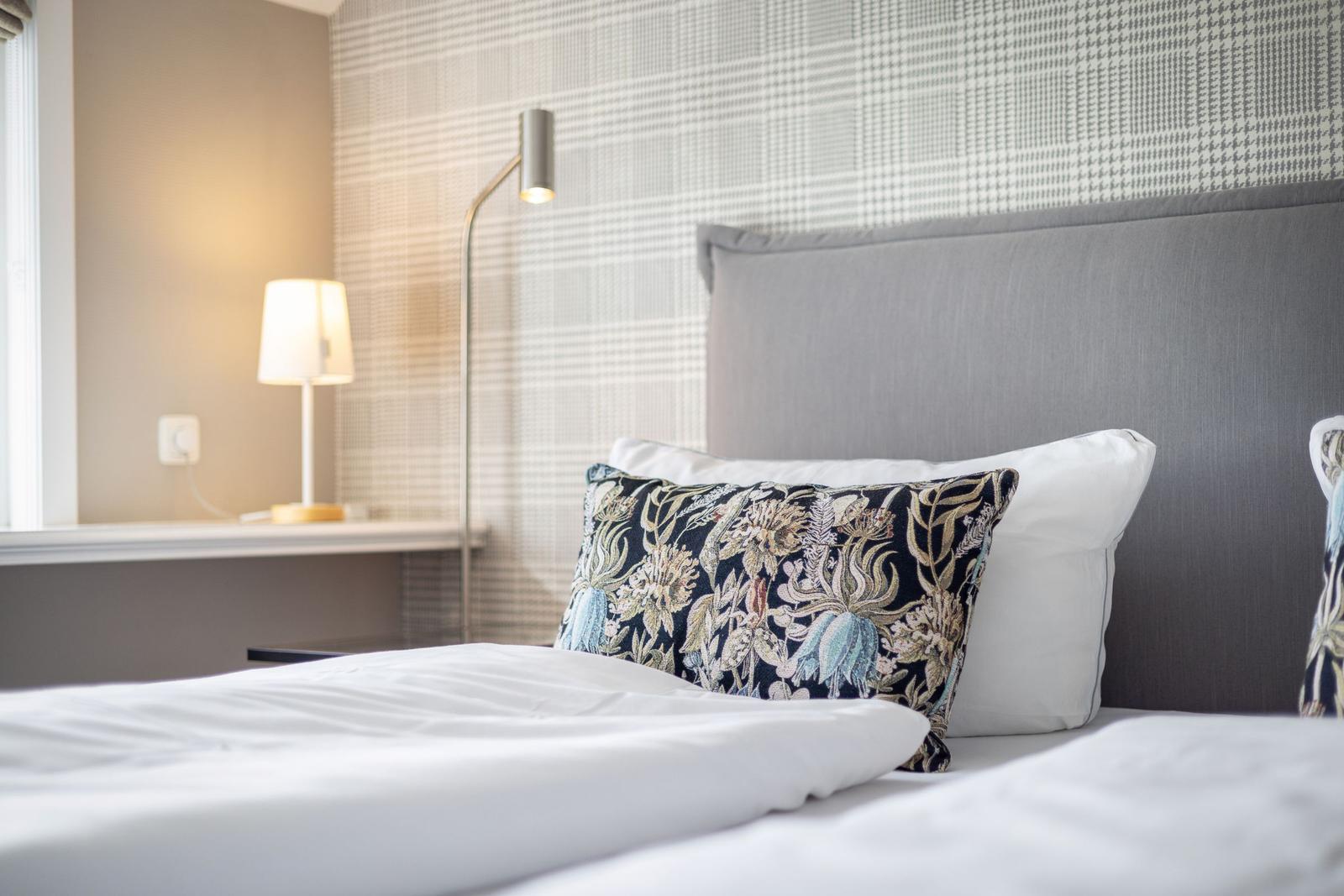 Schlafzimmer mit Bett, Kissen und Stehlampe.