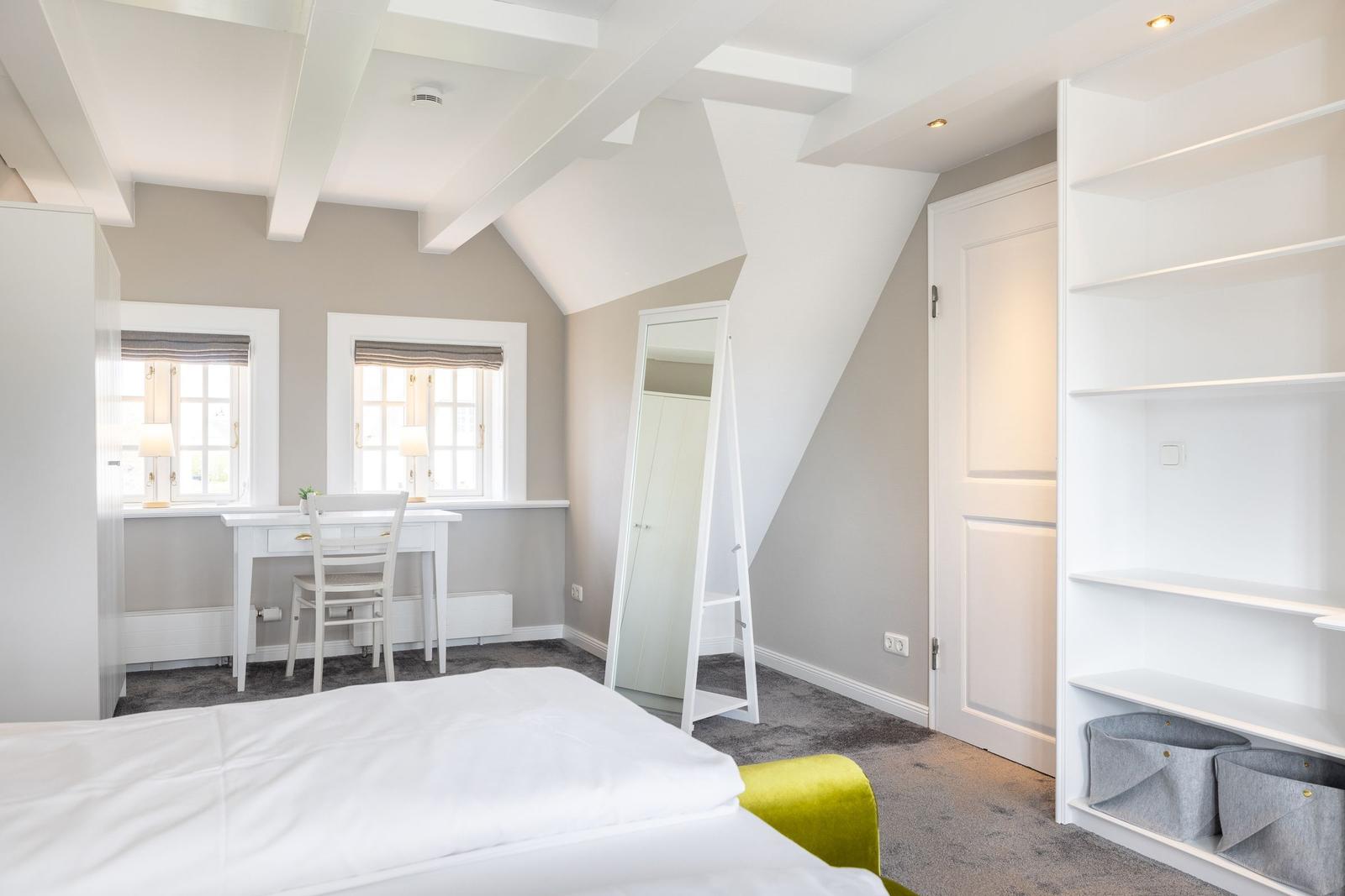 Schlafzimmer mit Dachschrägen, Schreibtisch und Kleiderschrank.
