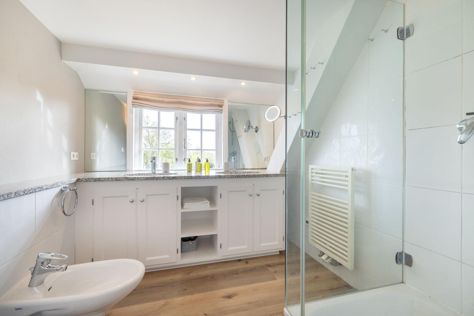 Badezimmer mit Dusche, Waschbecken und Fenster