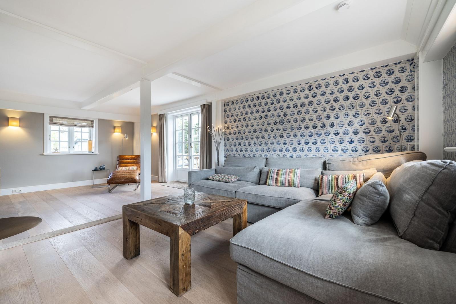 Wohnzimmer mit grauem Sofa, Holztisch und blau-weißem Tapetenwand.