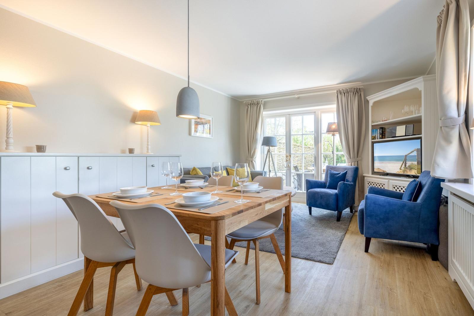 Esszimmer mit Tisch und Stühlen, Wohnbereich mit blauen Sesseln und TV.