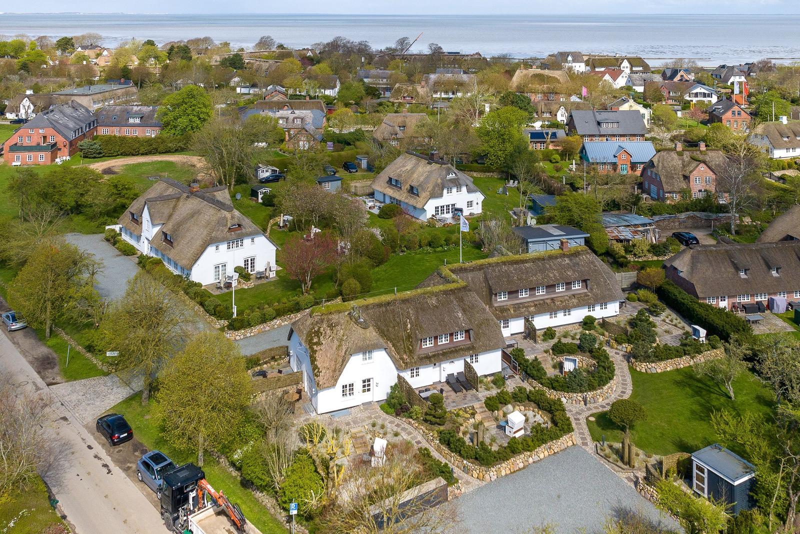 Dorf mit strohgedeckten Häusern und grünen Gärten am Wasser