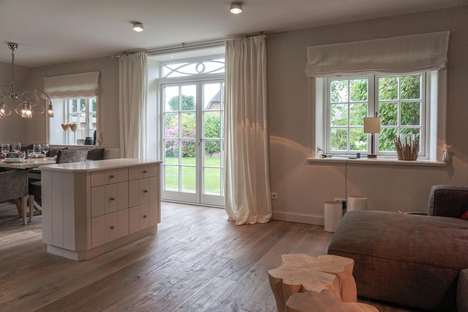Living and dining area with wooden floor, windows, and a kitchen island.