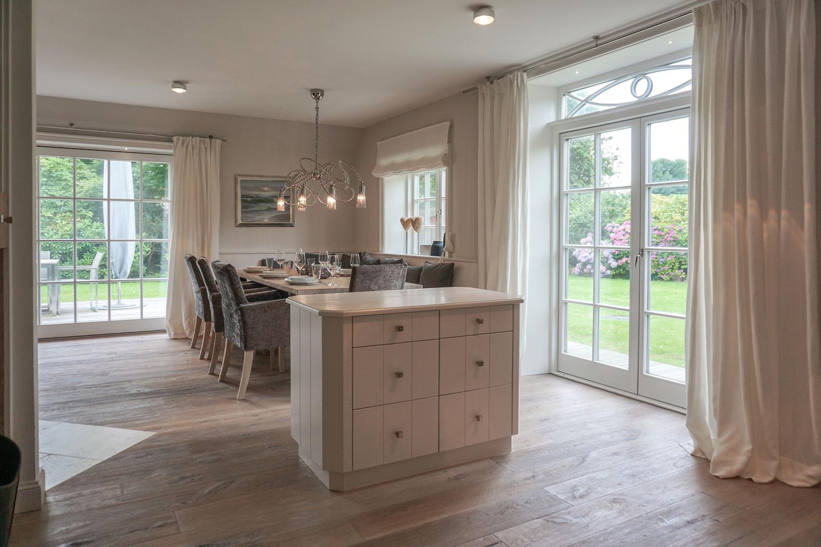 Dining room with kitchen island, seating area, and glass doors to the garden.