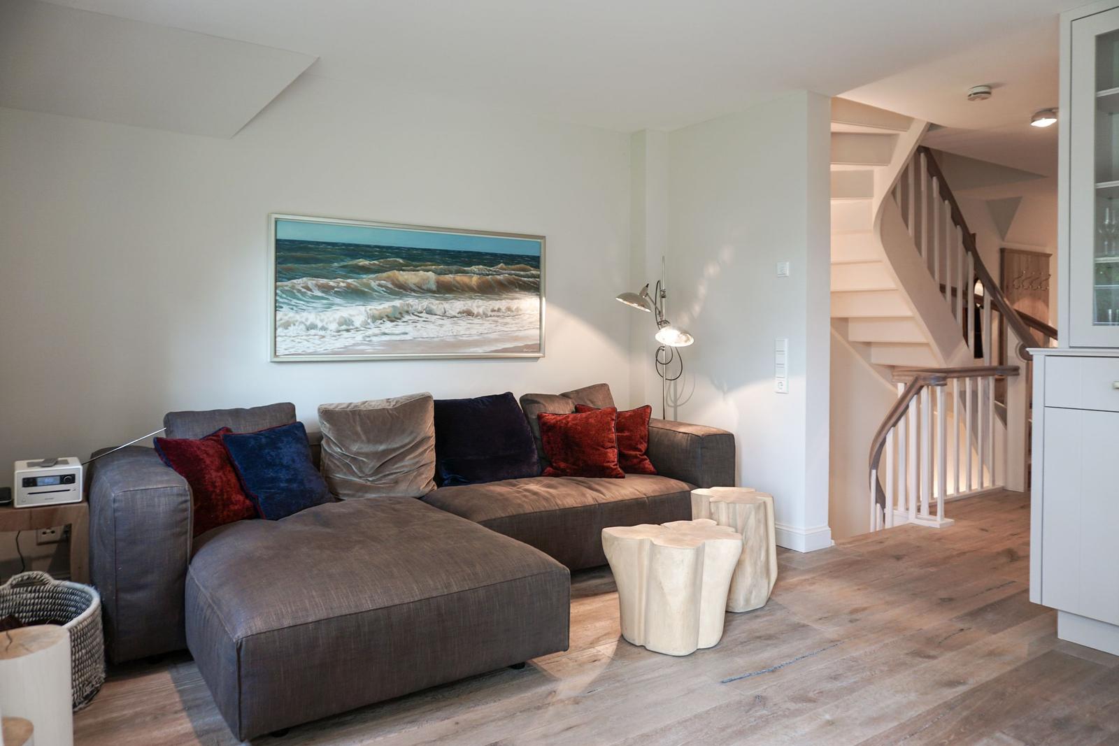 A living room with sofa, wall art, and staircase.