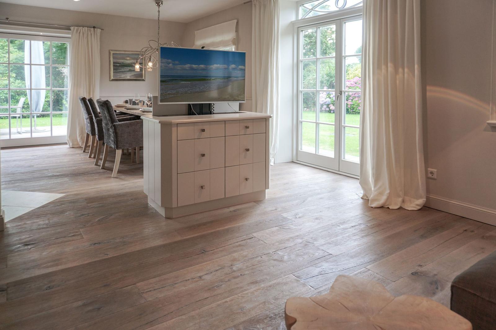 Living and dining area with TV stand, wooden floor, and glass doors to terrace.
