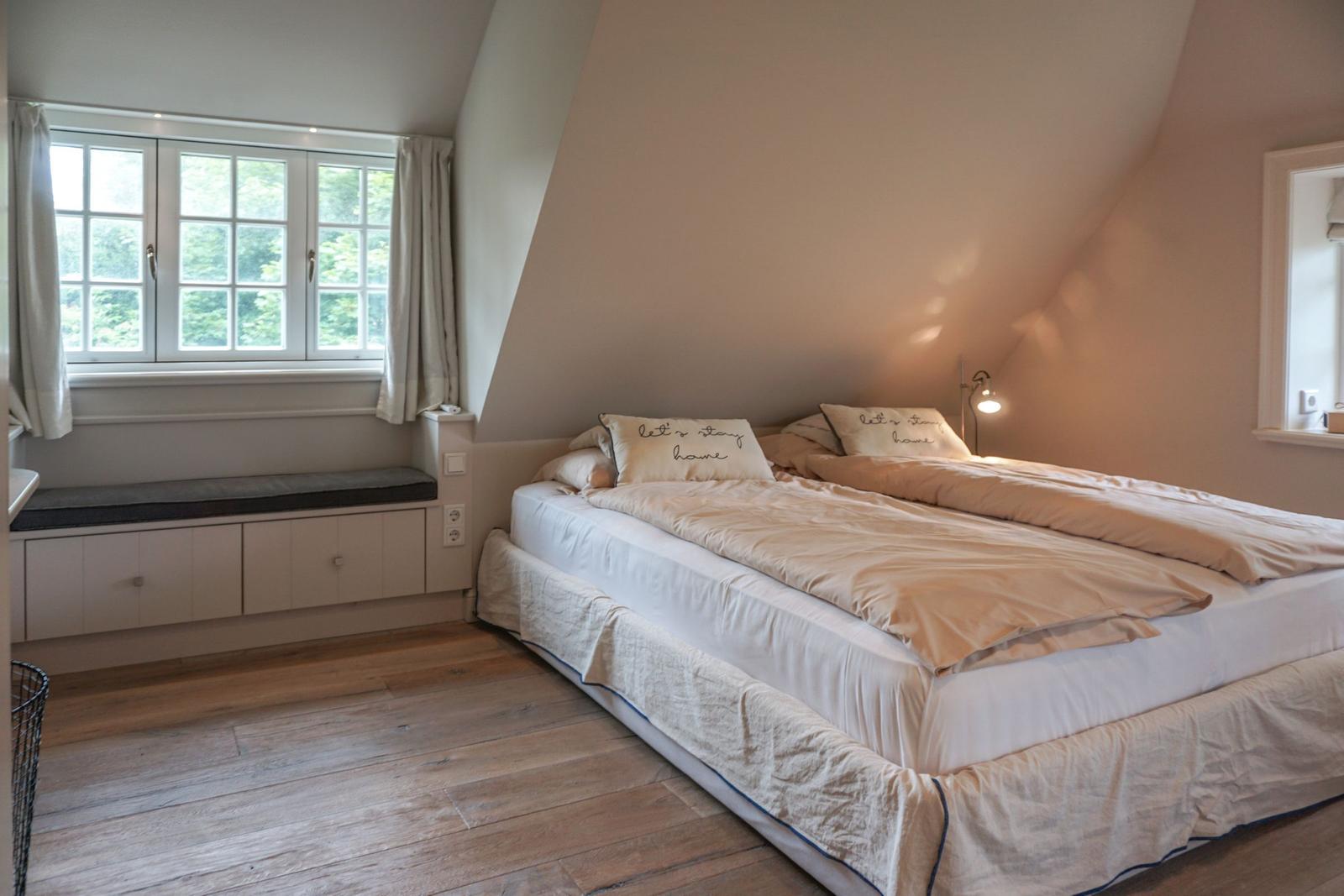 Bedroom with double bed, window, and wooden floor.