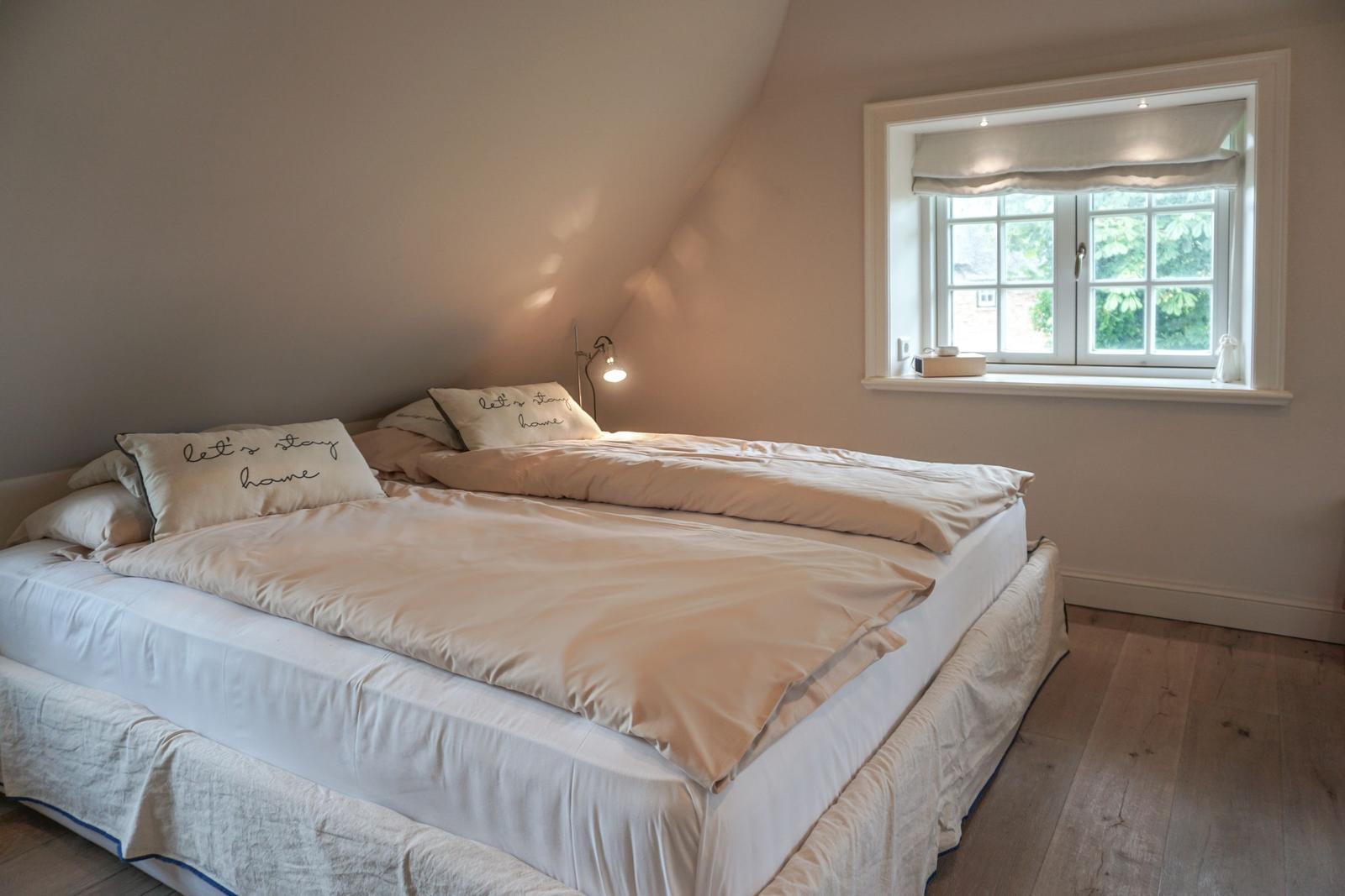 Bedroom with double bed, window, and wooden floor.