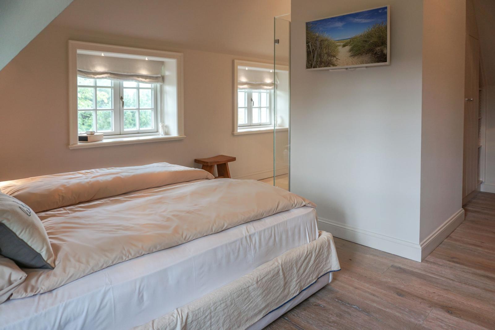 Bedroom with double bed, windows, and glass-walled shower.