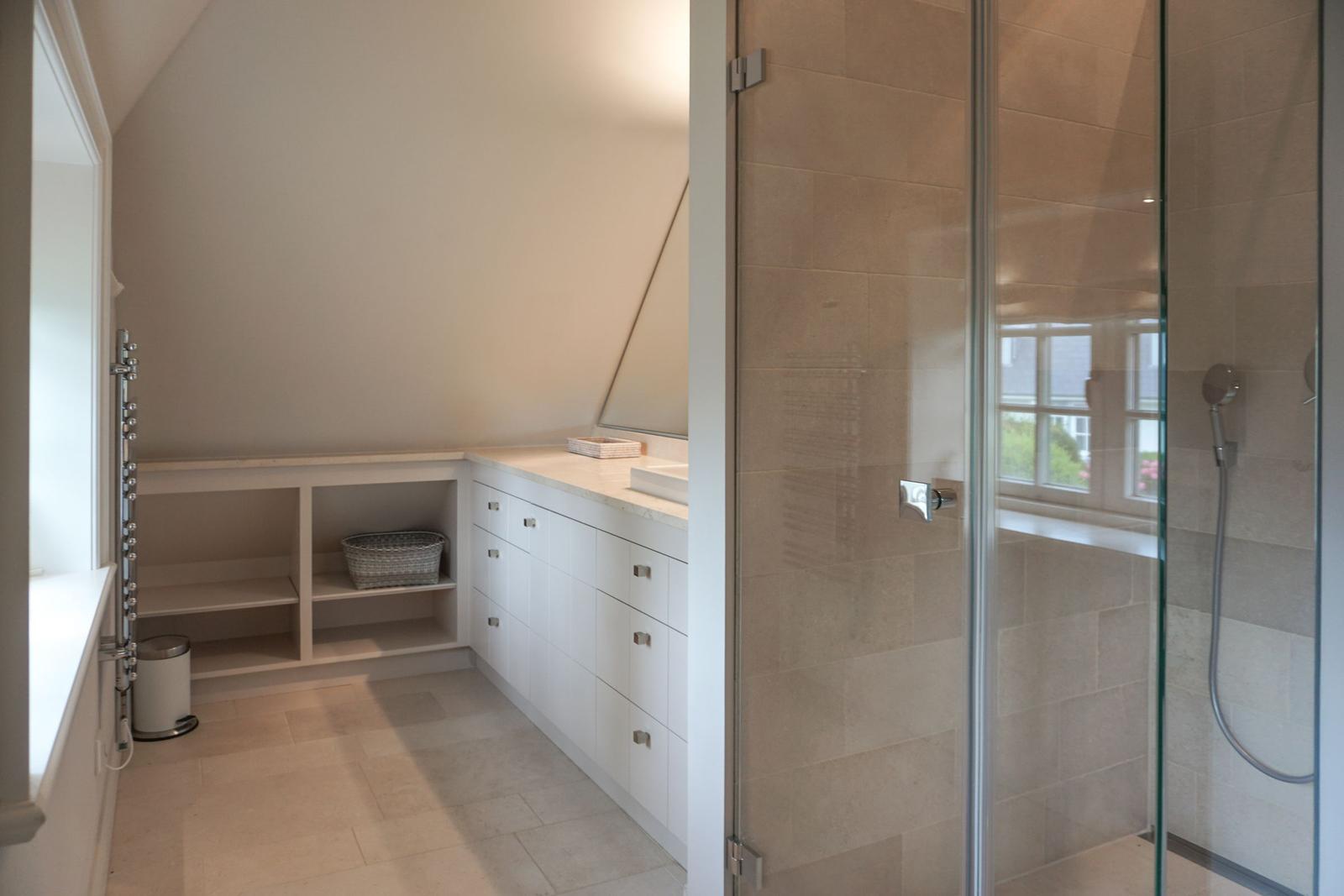 Bathroom with shower and sink. White cabinets and tiles.