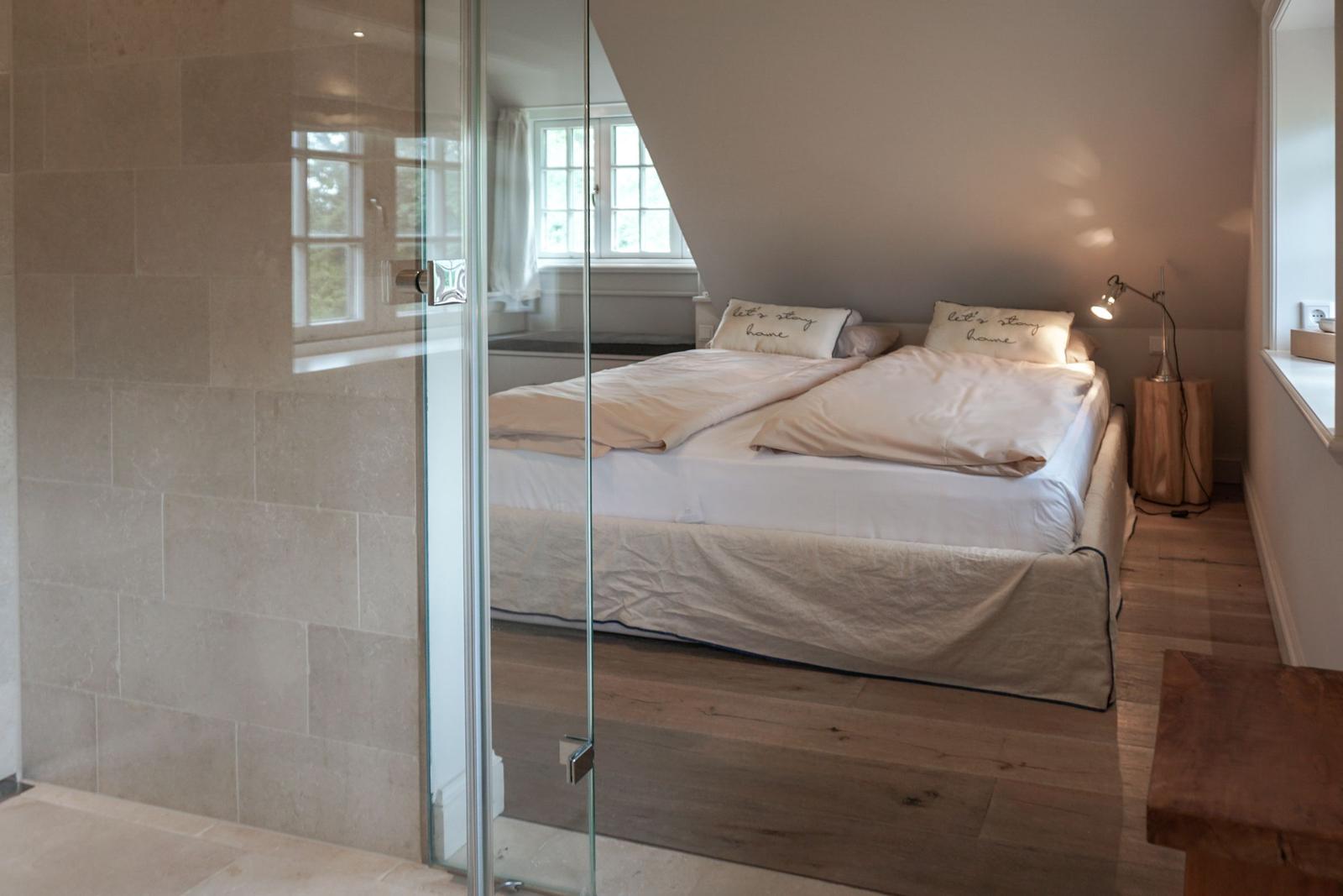 Bedroom with double bed, glass wall, and wooden floor.