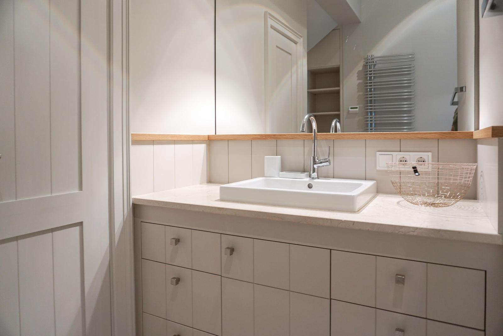 Bathroom with sink, mirror, and wooden top edge.
