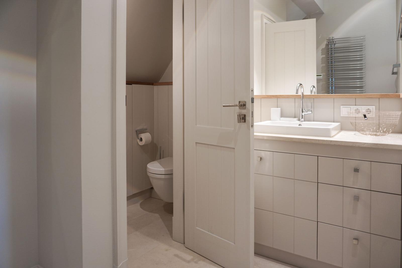 Bathroom with sink, mirror and toilet in continuation