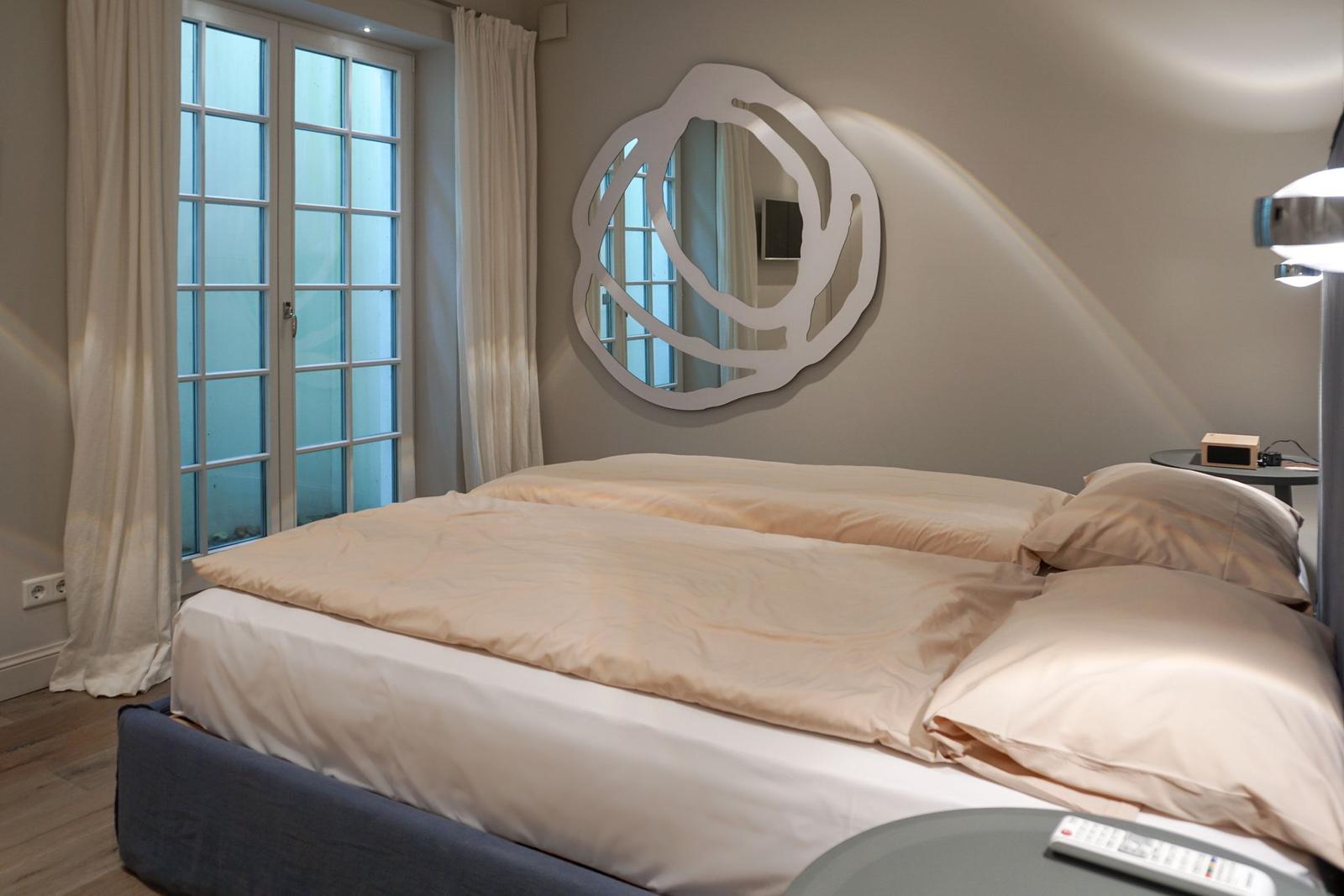 Bedroom with double bed, window, and wall mirror.