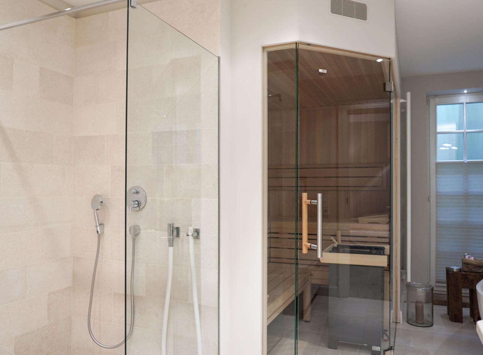 Shower with glass enclosure and sauna with wooden benches