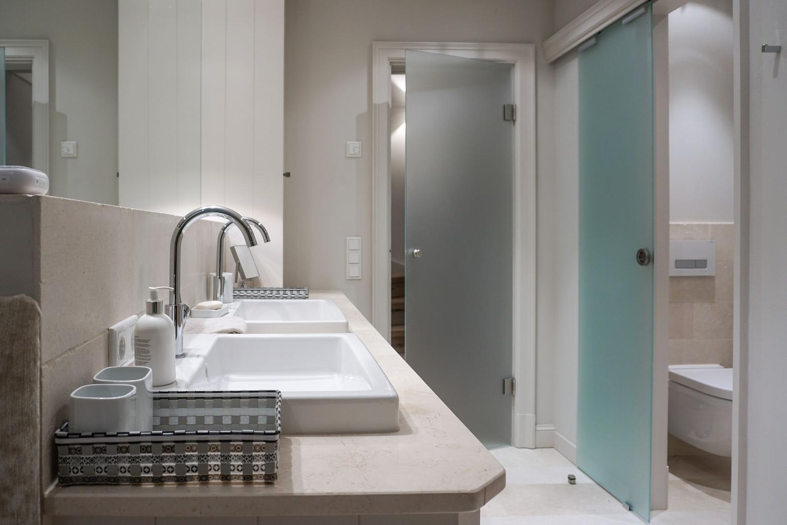Bathroom with two sinks, mirror, and shower with glass door.