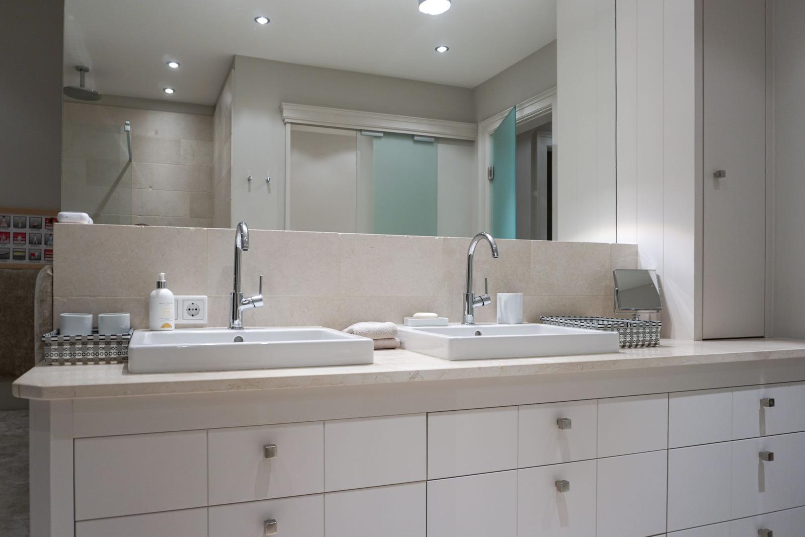 Double sink with mirrors and cabinets in modern bathroom setup.