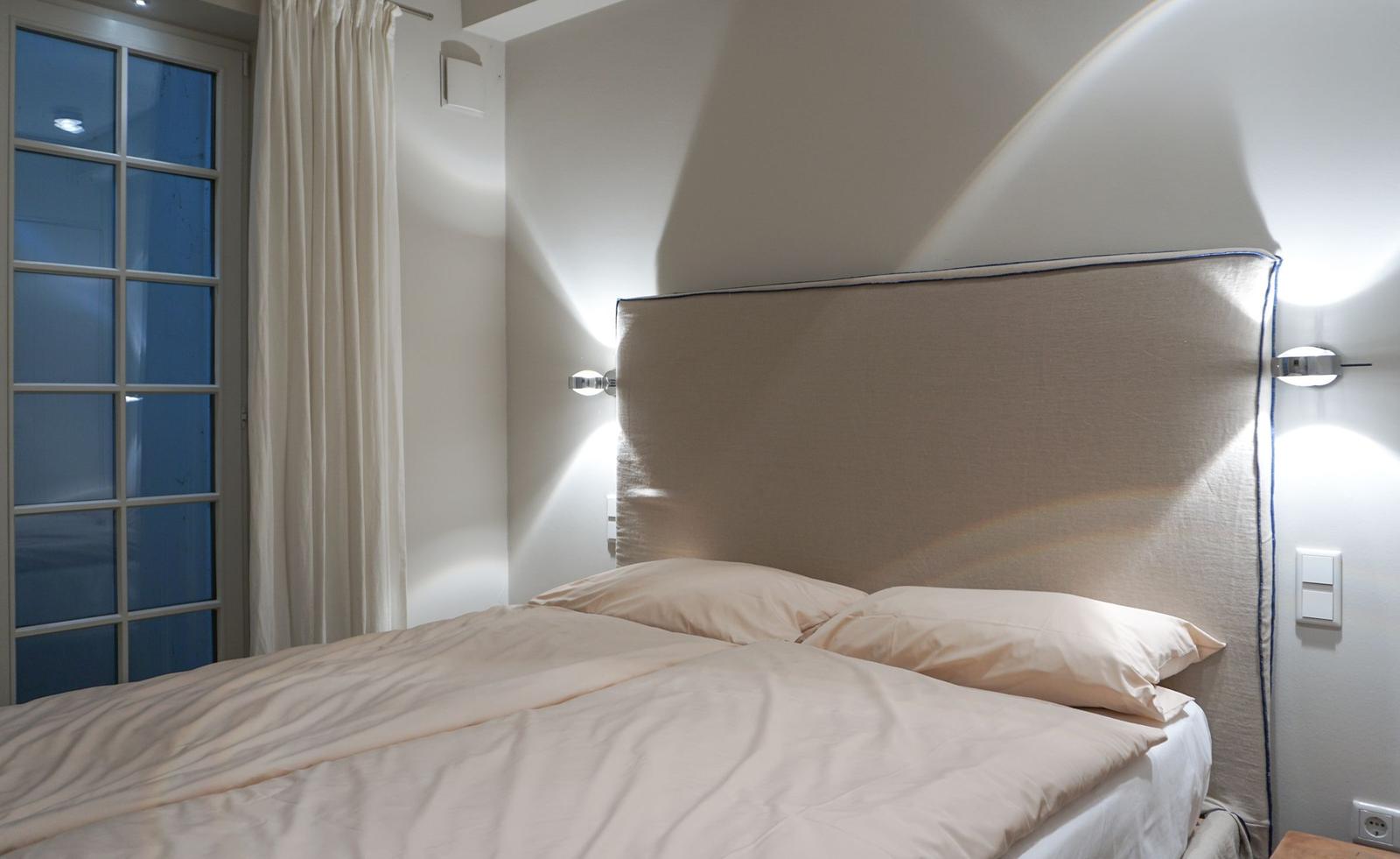 Bedroom with double bed, headboard, and window with curtains.