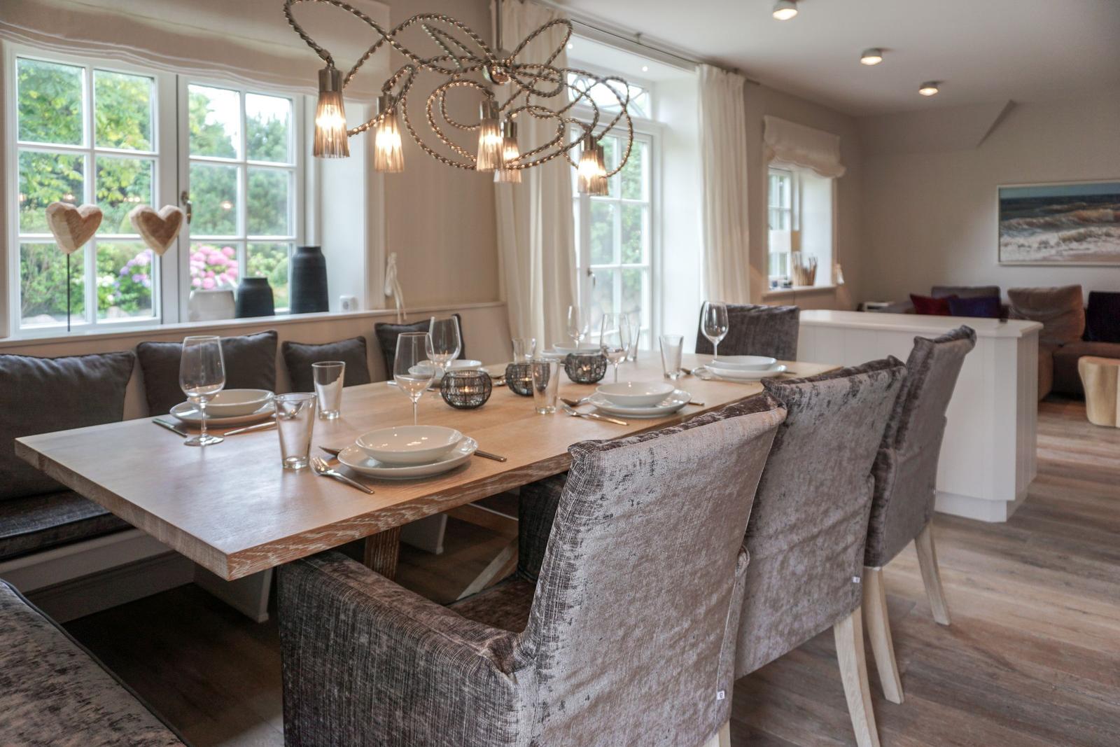 Dining room with table, chairs, and windows. Pendant lamp and bench are visible.