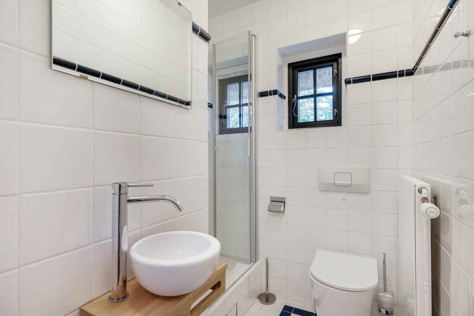 Badezimmer mit Dusche, Toilette und Waschbecken auf Holzuntersetzer.