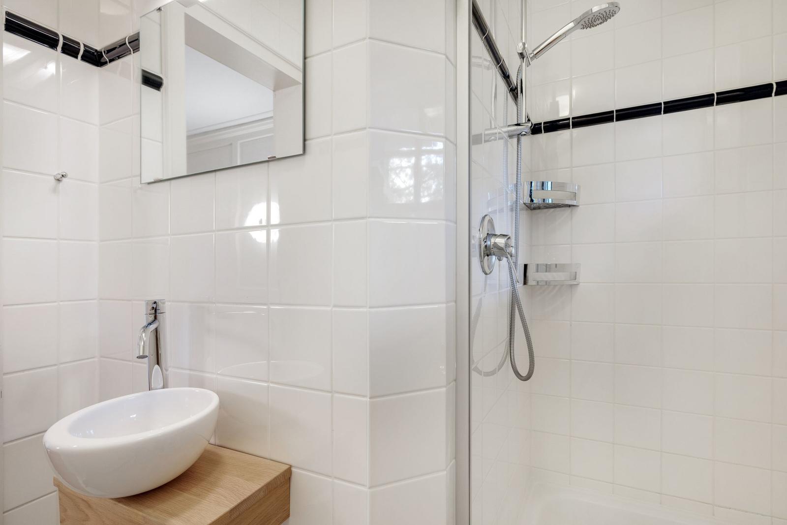 Badezimmer mit Dusche, Waschbecken und Spiegel
