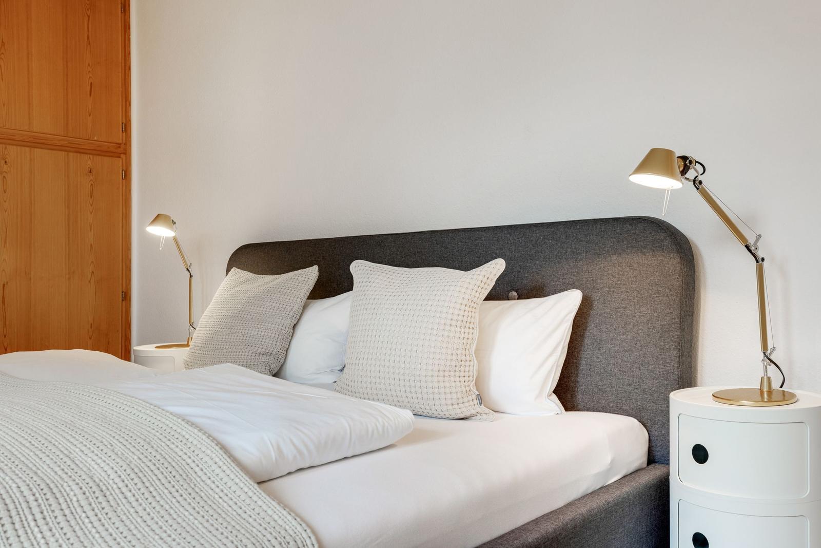 Schlafzimmer mit Bett, Kissen und Nachttischen mit Lampen.