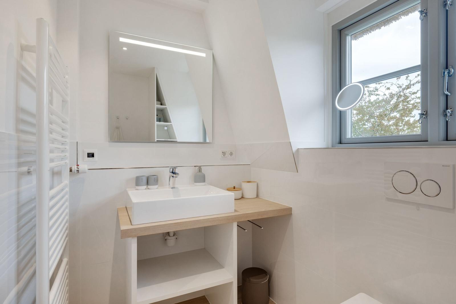 Badezimmer mit Waschbecken, Spiegel und Fenster.