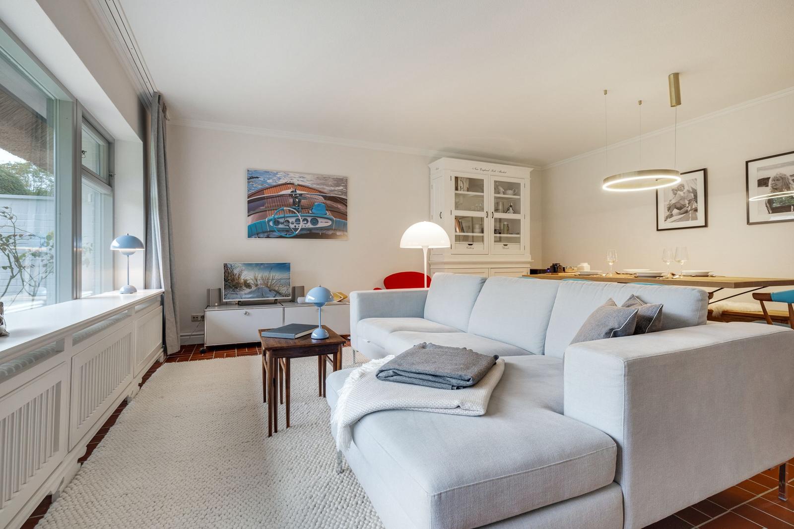 Wohnzimmer mit Sofa, Tisch und Fenster. Hintergrund: Wandbild und Schrank.